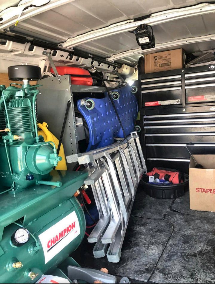 Interior of the van showing a Champion air compressor, aluminium ramps, a ladder and a full Husky tool chest